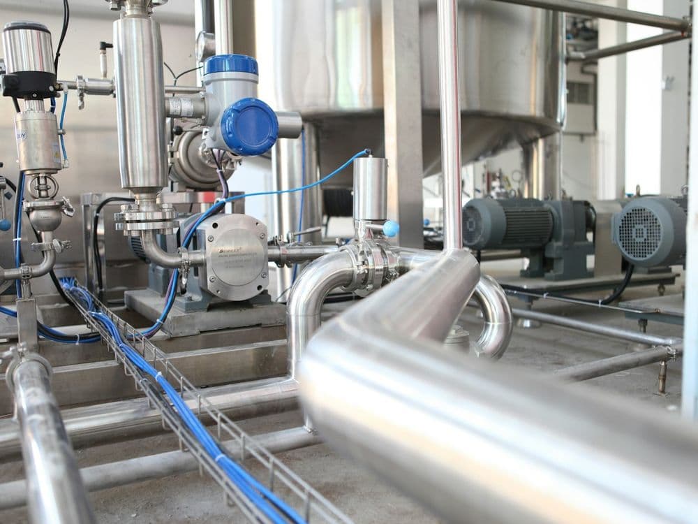 Close-up of stainless steel piping and pump fittings on a precision blending skid
